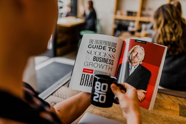 A person reads a magazine article about growing a business. 
