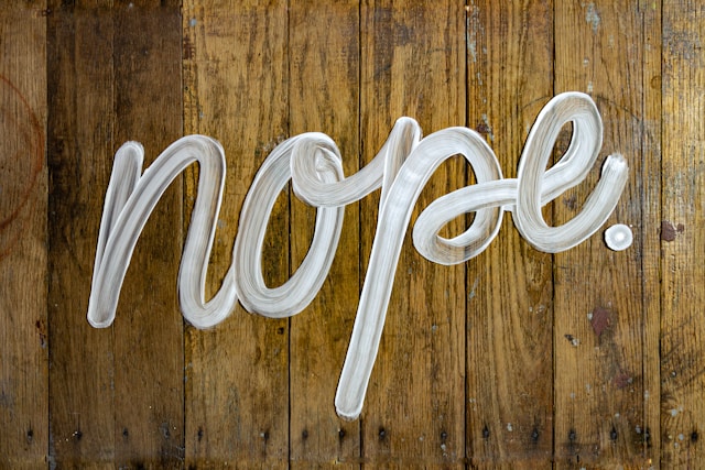 A wooden wall with the word “Nope” painted in white.