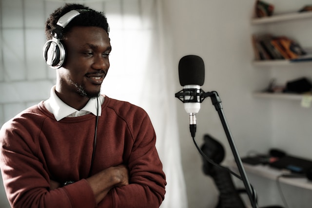 A content creator wears headphones and stands in front of a microphone for a TikTok LIVE. 
