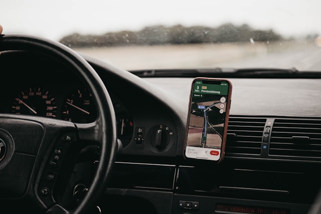 A smartphone inside a car displays a location app. 
