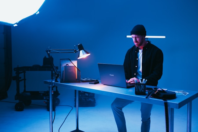 A man sits at a desk and edits TikTok videos on his laptop. 
