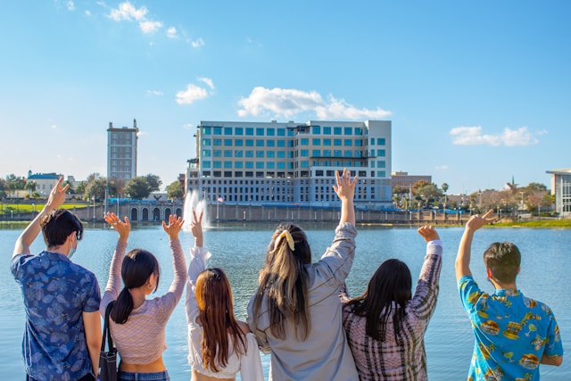 A group of people stands by a river and waves goodbye.