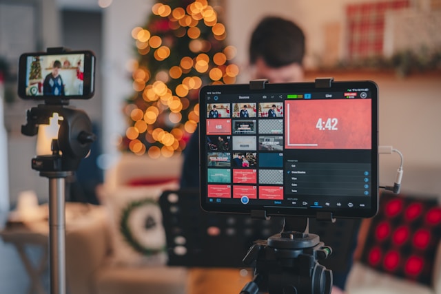 A phone camera and tablet are set up in front of a content creator for a TikTok live stream.