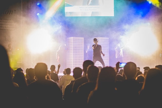 A big audience watches a man singing on a stage. 
