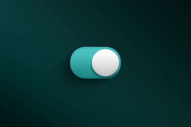 A blue and white on and off button on a green surface.
