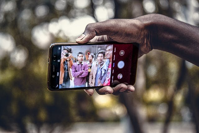 A phone screen shows multiple people in a photo.
