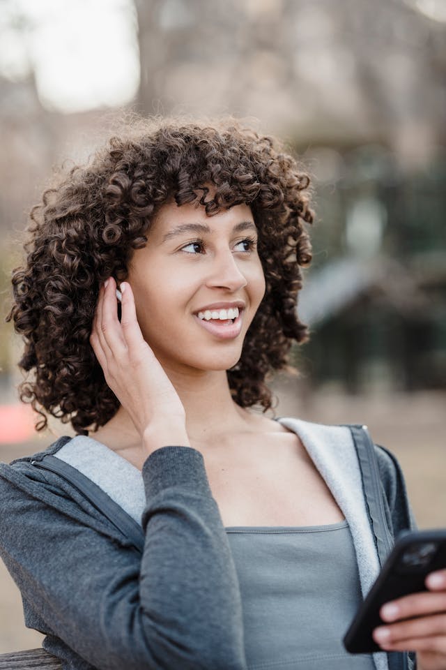 A woman with curly hair holds her cell phone.
