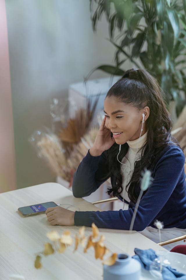 A woman smiles as she uses her phone at her desk.
