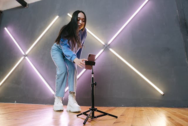 A woman sets up her phone on a tripod.