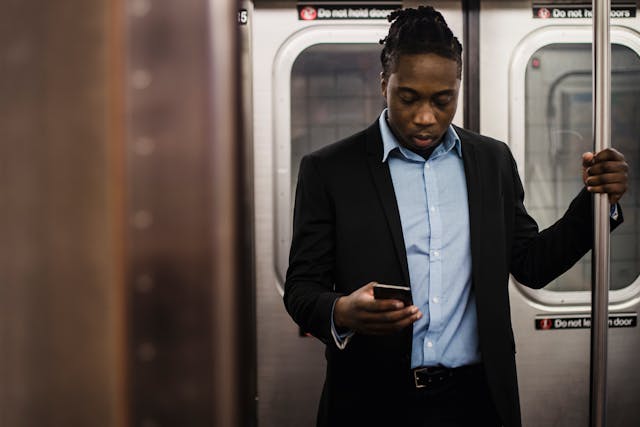 A man uses his phone while on a subway.
