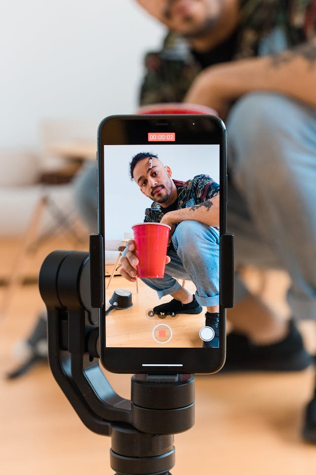 Un homme approche un gobelet rouge de l'objectif de son téléphone portable qui l'enregistre.