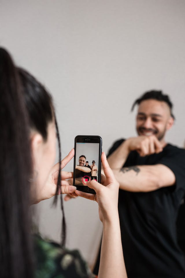 A woman records her friend performing dance choreography.
