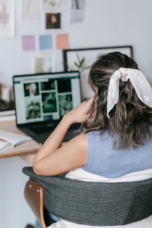 A woman with a bow in her hair types on her laptop.
