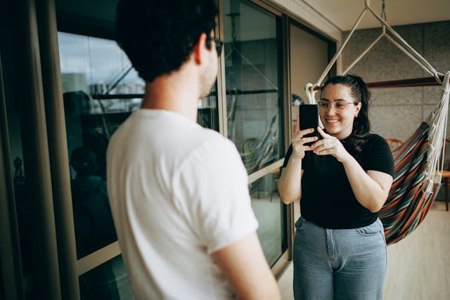 A woman takes a photo of a man.
