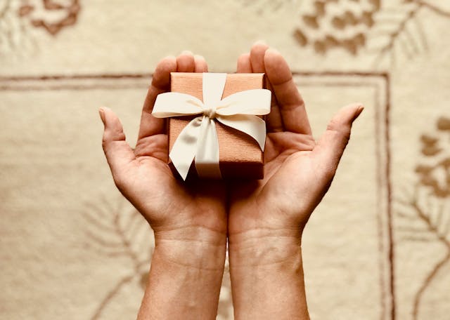 Hands hold a small gift box.
