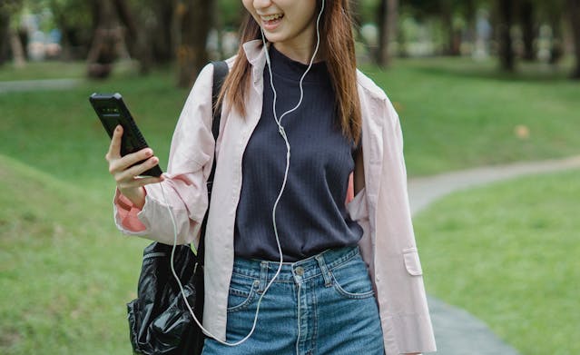 A woman grins as she looks at her cell phone.
