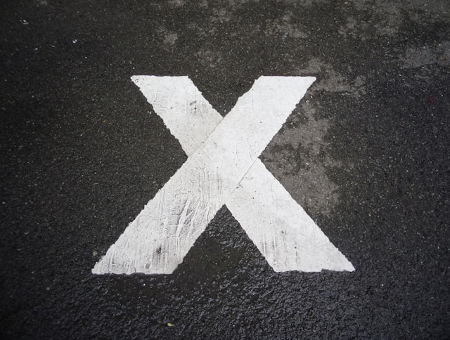 A white X sign painted on the pavement. 
