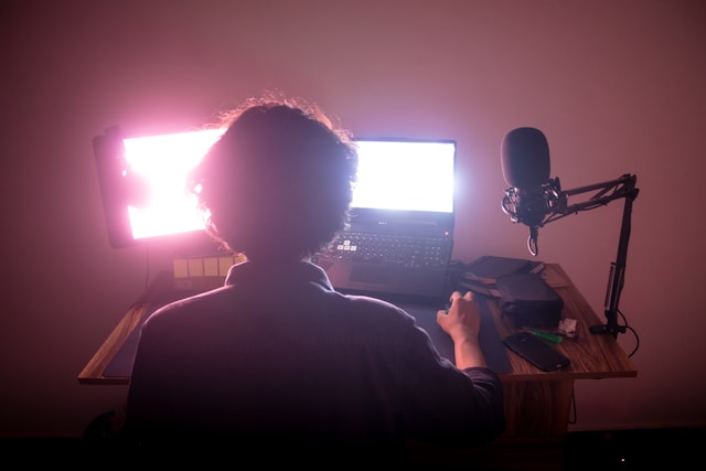 A content creator sits in front of two monitors and edits videos for TikTok. 
