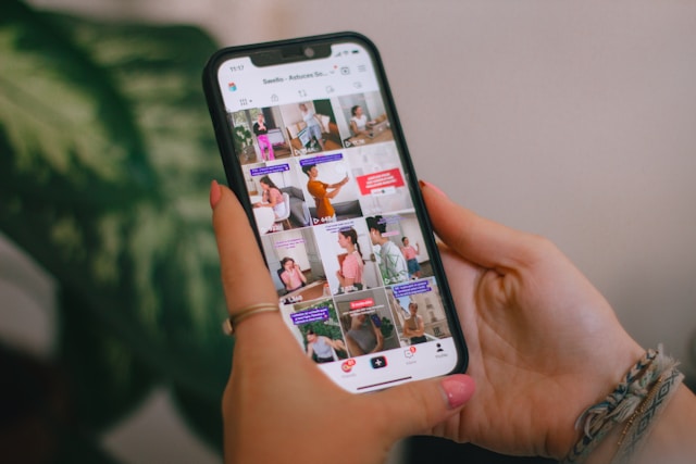 A person browses through a grid of TikTok videos on their phone. 
