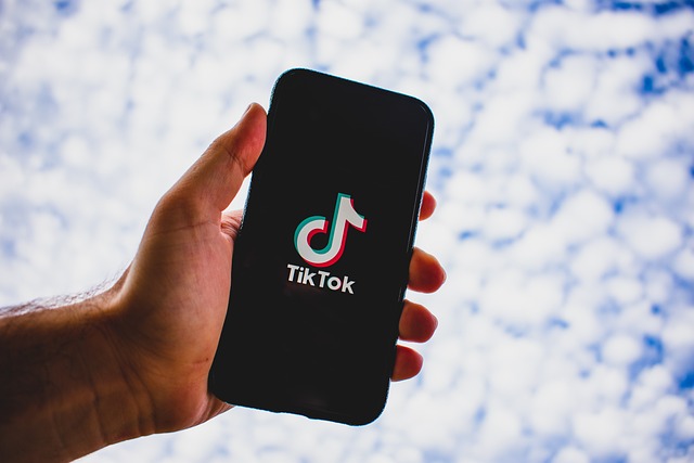 A person holds a phone with the TikTok logo on the screen.
