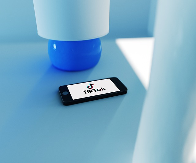 Um smartphone está sobre uma mesa azul com o logotipo do TikTok na tela.