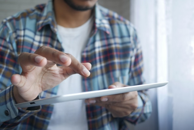 A person’s finger hovers over the screen of a tablet. 
