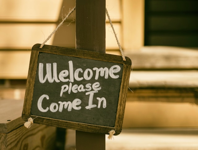 A sign on a small chalkboard says, “Welcome, please come in.”
