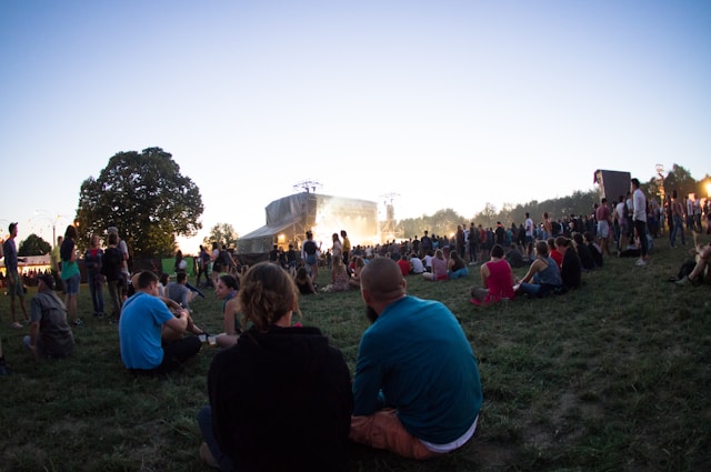 A big crowd gathers for a live performance at a park.
