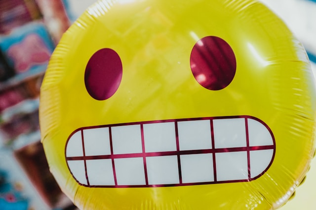 A yellow balloon with a grimacing face printed on it. 
