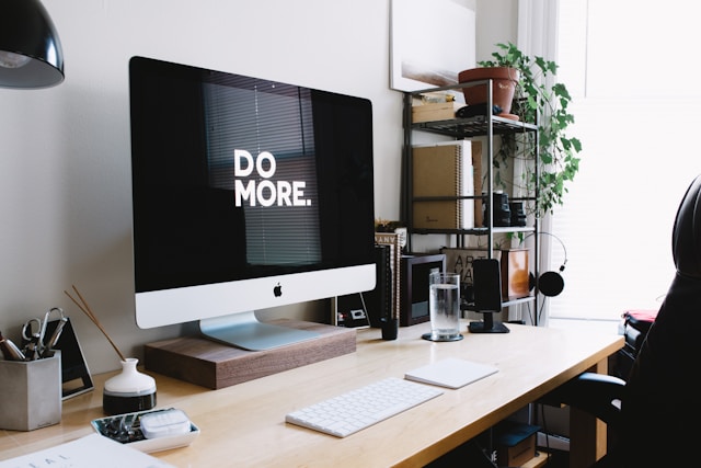 A big Apple monitor displays the words “Do more” on a black screen. 
