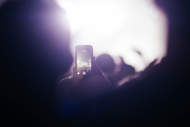 A person at a concert livestreams the performance using their phone. 
