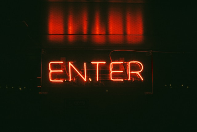 A red, lighted sign says, “Enter.”
