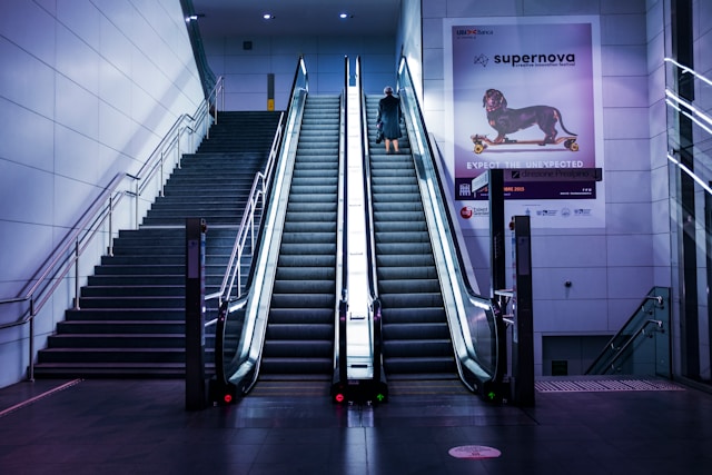 A woman on an escalator going up. 
