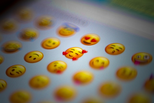 A phone screen displays popular face emojis. 
