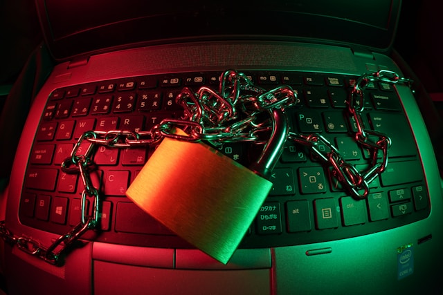 A padlock and a chain on top of a laptop keyboard. 
