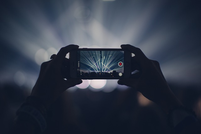 A person records a video on their phone during a concert.
