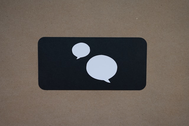 Two, white chat bubbles on a black background in the shape of a phone.