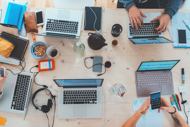 A group of content creators sit around a table and work on their laptops. 
