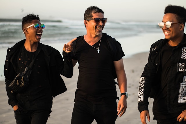 A father and his two sons share a laugh at the beach. 
