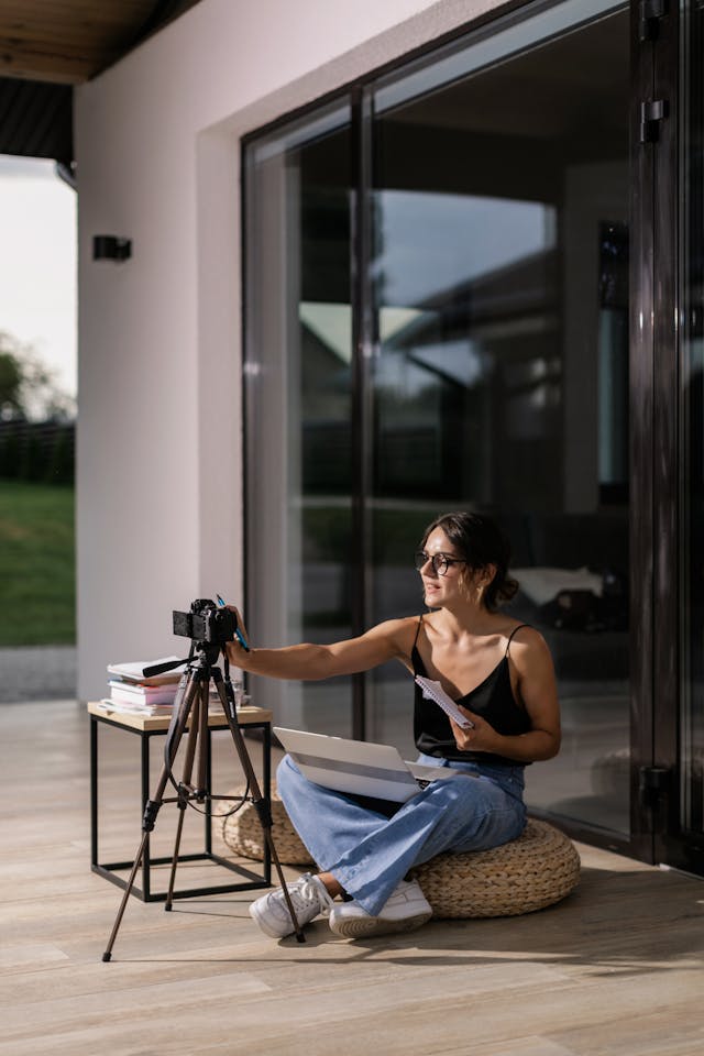 A woman sets up her camera outside her front door.
