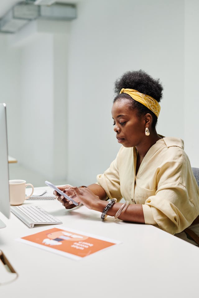 A woman types on her cell phone with a serious expression.
