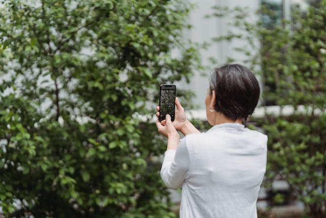 A woman takes a photo outside using her phone.
