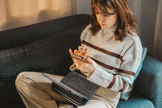 A woman uses a phone over her tablet.
