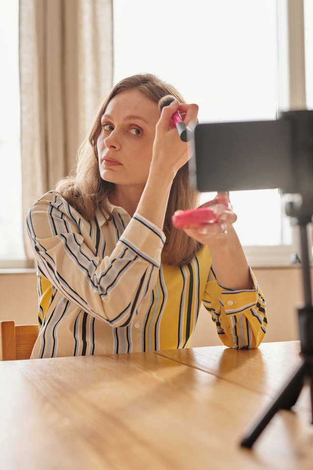 A woman records herself applying makeup.
