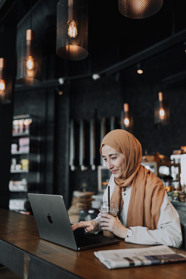 A woman types on her laptop at a coffee shop.
