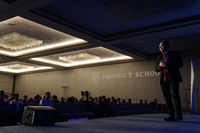 A speaker stands on a stage in front of an engaged audience. 
