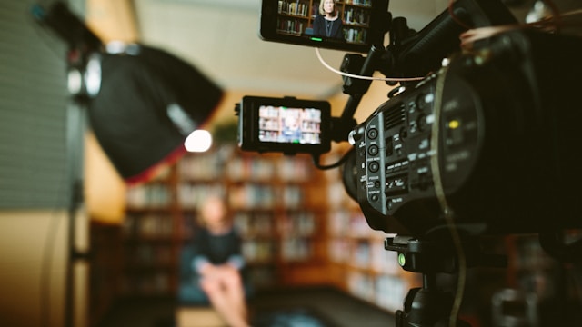 A woman sits in a bookstore in front of a video camera for a TikTok LIVE. 
