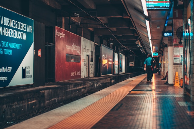 Big billboards cover one side of a train platform. 
