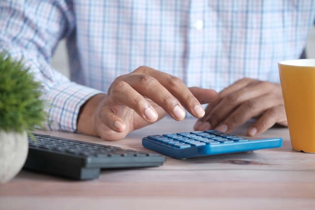 A person uses a blue calculator to calculate his ad spend. 
