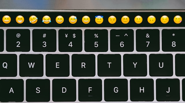 A black keyboard features a row of face emojis at the top. 
